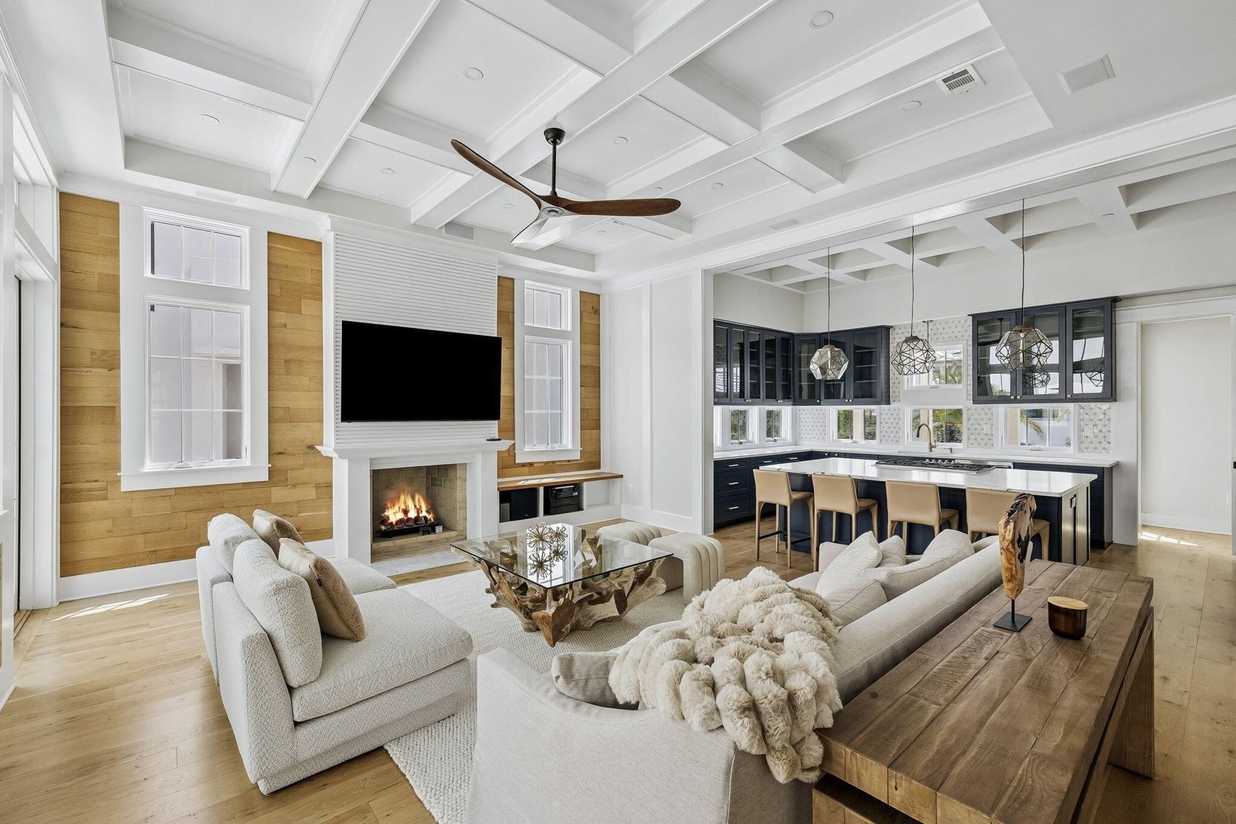 A coastal living room with a fireplace and open kitchen beyond, from a 30A listing